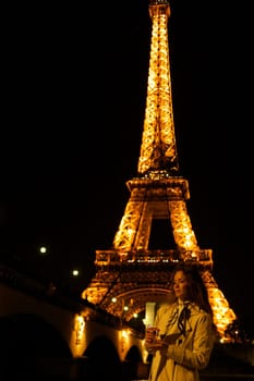 Girl with a glass against the backdrop of the glowing Eiffel Tower in. High quality photo