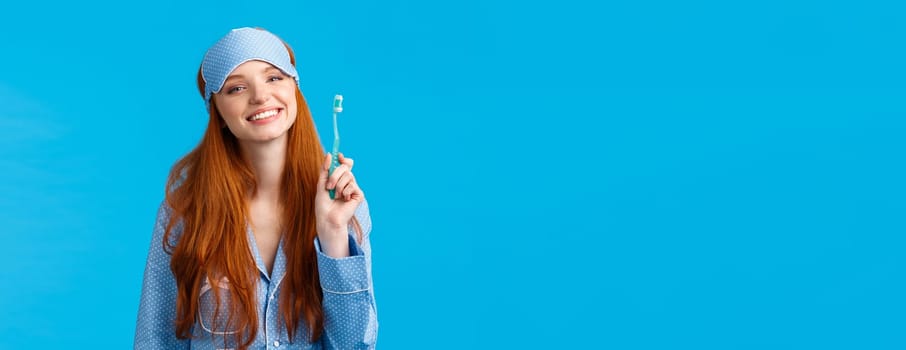 Health, lifestyle and beauty concept. Cheerful cute glamour redhead woman in nightwear and sleep mask, smiling happily, start morning brushing teeth and taking care personal hygiene.