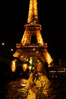 Girl with a glass against the backdrop of the glowing Eiffel Tower in. High quality photo