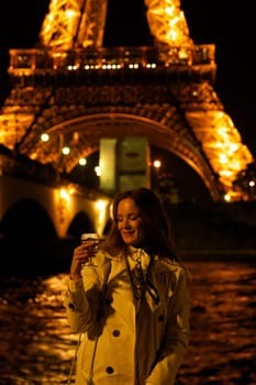Girl with a glass against the backdrop of the glowing Eiffel Tower in. High quality photo