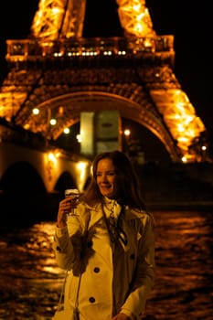 Girl with a glass against the backdrop of the glowing Eiffel Tower in. High quality photo