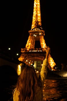 Girl with a glass against the backdrop of the glowing Eiffel Tower in. High quality photo