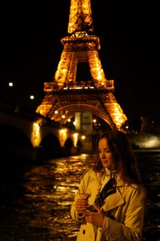 Girl with a glass against the backdrop of the glowing Eiffel Tower in. High quality photo