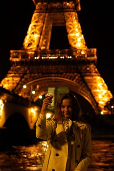 Girl with a glass against the backdrop of the glowing Eiffel Tower in. High quality photo