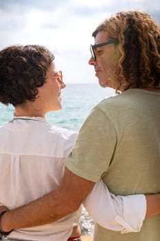 Smiling couple wearing sunglasses enjoying a vacation embracing looking at the sea.Vertical