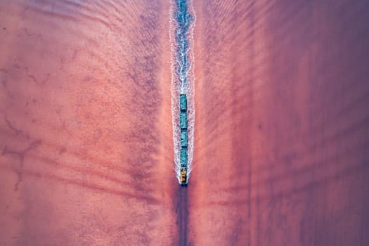 Aerial top down view of an old train rides on the railway laid in the water through the salt lake. Salt mining in Lake Burlin. Altai. Bursol.