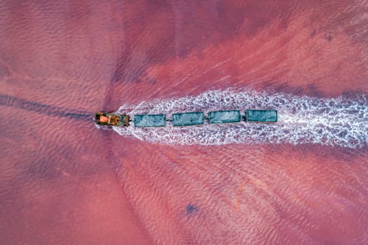 Aerial top down view of an old train rides on the railway laid in the water through the salt lake. Salt mining in Lake Burlin. Altai. Bursol.