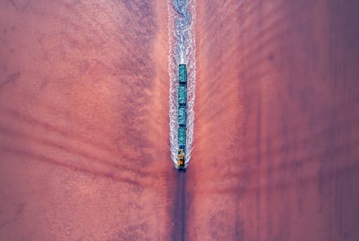 Aerial top down view of an old train rides on the railway laid in the water through the salt lake. Salt mining in Lake Burlin. Altai. Bursol.