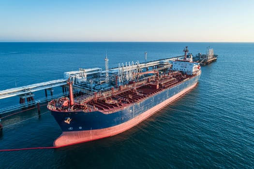 Aerial view of a large oil tanker docked at a pier in the port in process of loading.