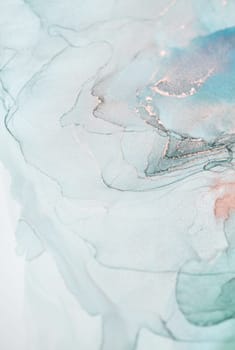 A close-up shot of an abstract painting created with teal and silver ink. The swirls and patterns create a mesmerizing and ethereal effect.