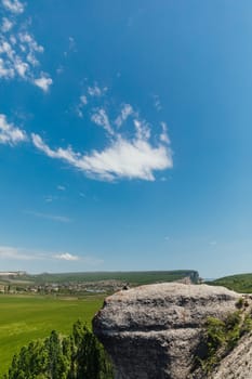 woman sitting on cliff far away mountainous nature and blue sky hike