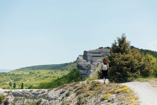 woman on hike with a backpack walk on the mountain of rocks nature walks along the road