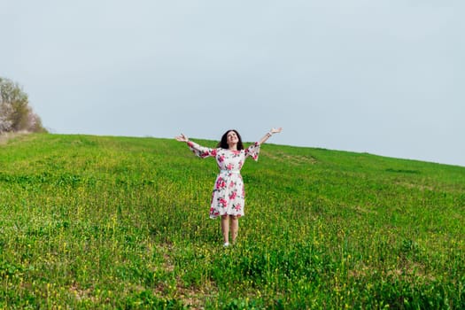 woman with her hands up standing on a green field walk