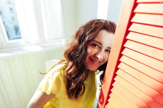 woman sits near a red screen in a bright room