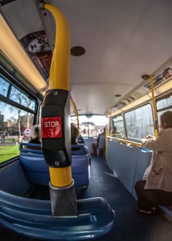 London, United Kingdom - March 17, 2007: Extreme wide (fisheye) photo, public transport bus, with blurred passengers commuting on sunny day, focus to STOP request button.