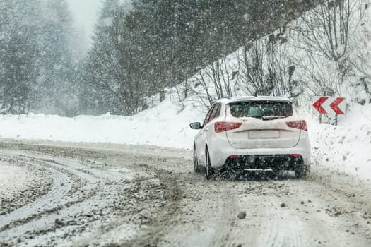 Vysna Boca, Slovakia - January 08, 2019: Car drives through heavy snowstorm on forest road, in sharp curve. Driving conditions are often dangerous in winter.