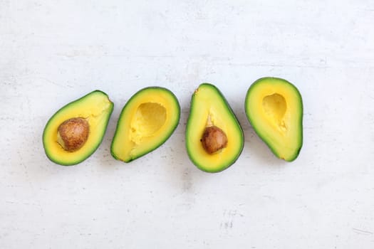 Top down view, two avocados cut in half, halves with seed visible , on white stone like board. Space for text above, and below.