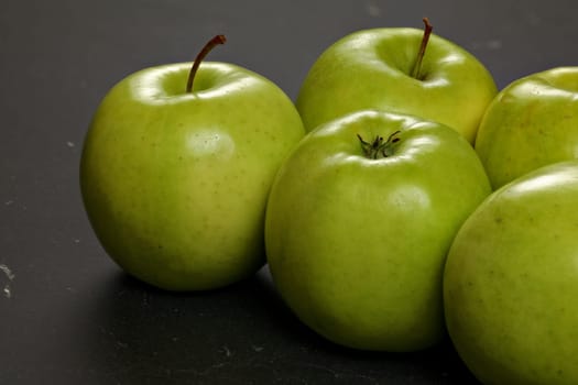 Closeup of green apples on black board