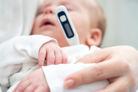 Newborn in deep sleep held by mother as she uses a modern thermometer to detect potential sickness