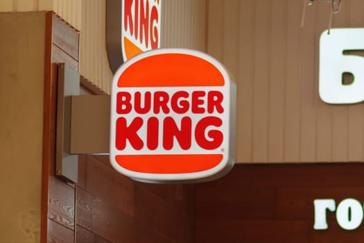 Tyumen, Russia-June 20, 2024: Burger King side. The sign is attached to a metal bracket and is visible in a brightly lit environment.