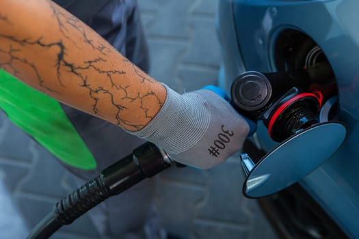 Hand Man Refill and filling Oil Gas Fuel at station. Gun petrol in the tank to fill. Pumping gasoline fuel in car at gas station. Refueling automobile with gasoline or diesel with a fuel dispenser.