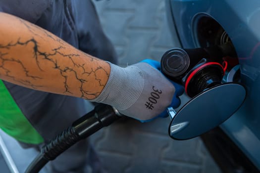 Hand Man Refill and filling Oil Gas Fuel at station. Gun petrol in the tank to fill. Pumping gasoline fuel in car at gas station. Refueling automobile with gasoline or diesel with a fuel dispenser.