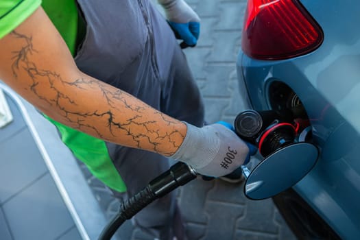Hand Man Refill and filling Oil Gas Fuel at station. Gun petrol in the tank to fill. Pumping gasoline fuel in car at gas station. Refueling automobile with gasoline or diesel with a fuel dispenser.