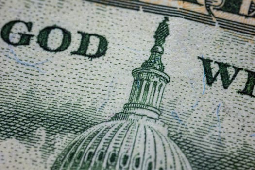A detailed photograph of U.S. currency displaying the Capitol Dome and part of the In God We Trust text