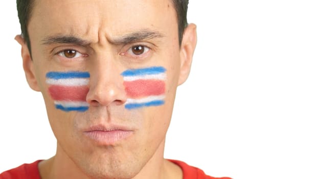 Close up of a serious man with a costa rican flag painted on the face looking at camera