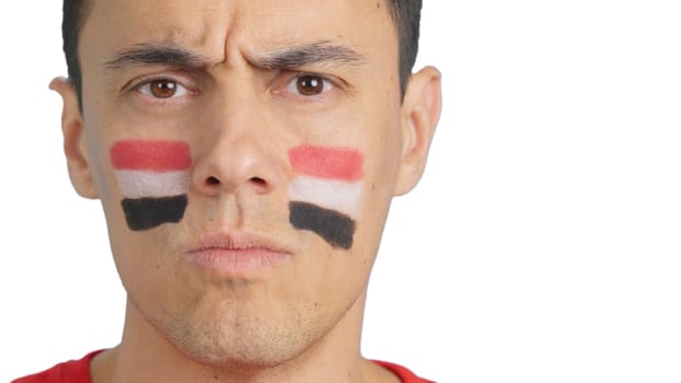 Close up of a serious man with a egyptian flag painted on the face looking at camera