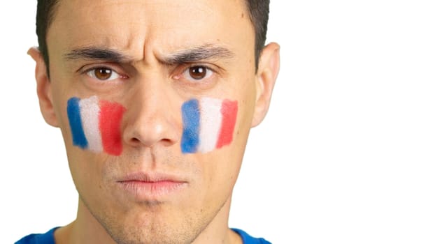 Close-up of a serious man with a french flag painted on the face looking at camera