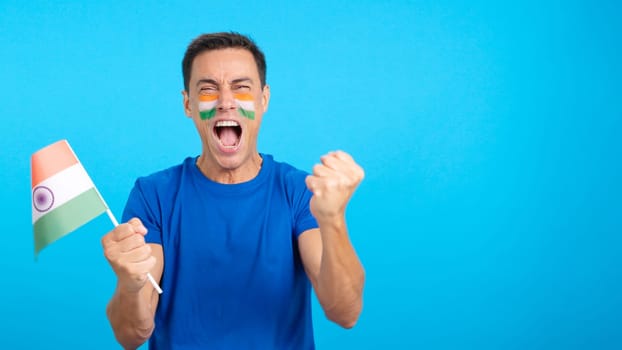 Indian supporter screaming and waving a national flag, cheering his team to victory and celebrating passionately