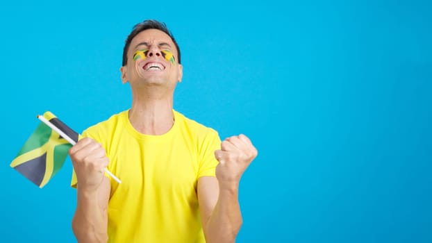 Man passionately cheering for Jamaica screaming and waving a national flag