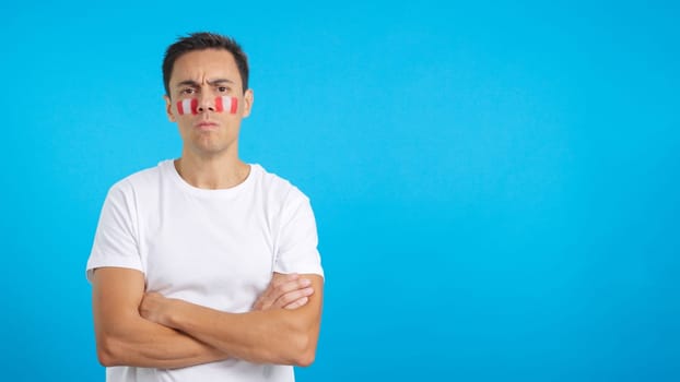 Dignified and serious man with peruvian flag painted on face looking the camera with dignity
