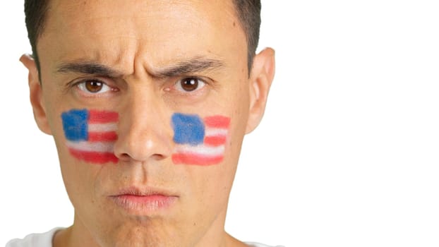 Close-up of a serious man with a United States flag painted on the face looking at camera