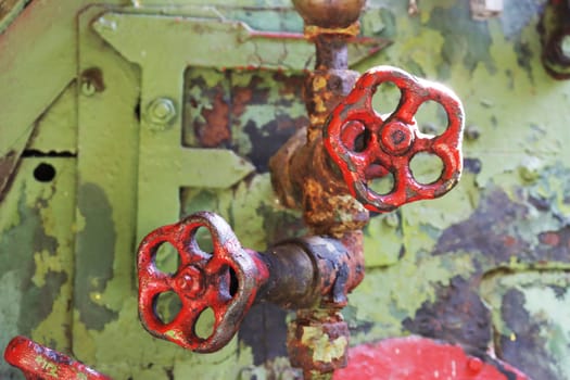 Two red shabby retro taps for shutting off the water close-up. Steam engine controls.