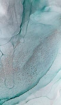 An abstract photograph of teal and white ink swirling together, creating a mesmerizing and organic pattern. The colors blend seamlessly, creating a sense of depth and movement.