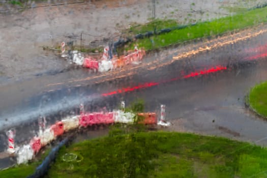 Shot of the light trails from the cars on the road, made trough window during the rain