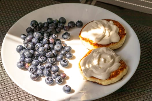 Shot of the breakfast plate with home made cheesecakes with sour cream and blueberries