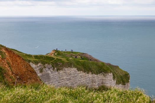 etretat,france,23-04-2024:people walking on the rocks and cliffs of etretat in france looking at the ocean