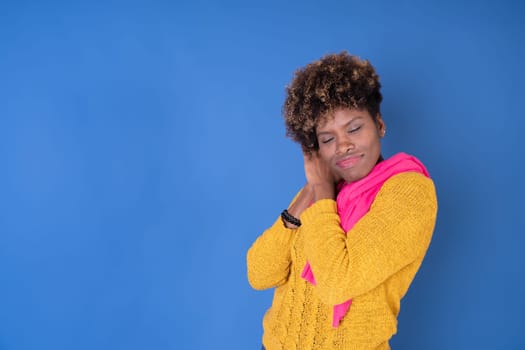 A woman in a yellow sweater is looking at the camera. She is wearing a pink scarf and has a black bracelet on her wrist