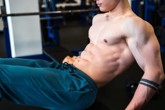 Bodybuilder doing abs workout on bench in gym.