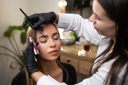 Beauty master styling clients eyebrows in a salon.