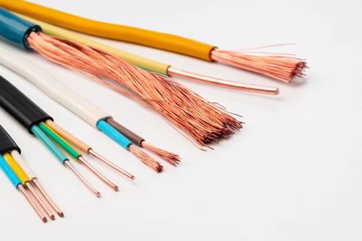 A close-up image showcasing various types of electrical wires with exposed copper strands on a white background.