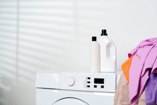 This image shows two white washing machines with a pile of colorful clothes sitting on top of one of them.