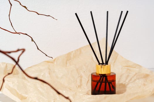 A glass diffuser bottle with wooden sticks sits on a wooden tabletop.