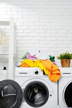 A pile of colorful laundry sits precariously on top of a white washing machine, ready to be washed.