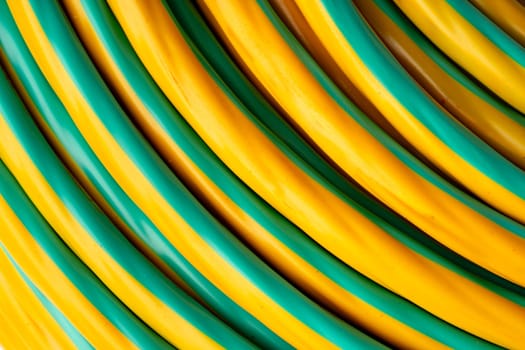 This image shows a close-up view of a coiled electrical cable. The cable is yellow with a green stripe running down the center.