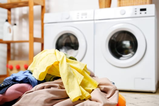 A photograph of a laundry room with two white washing machines and a wooden shelf filled with cleaning supplies.