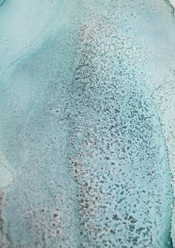 Close-up photograph of an abstract, textured surface with a light turquoise background and tiny, scattered dots.